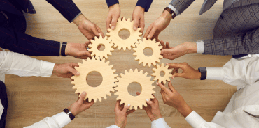 Group of hands holding interconnected gears, symbolizing the teal model